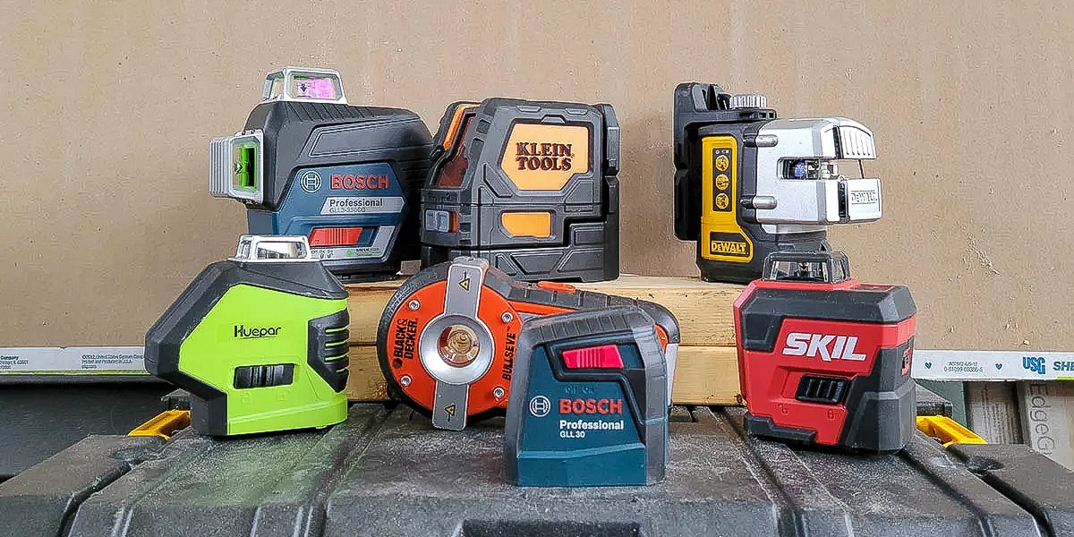 Laser levels of various brand names on a workbench.